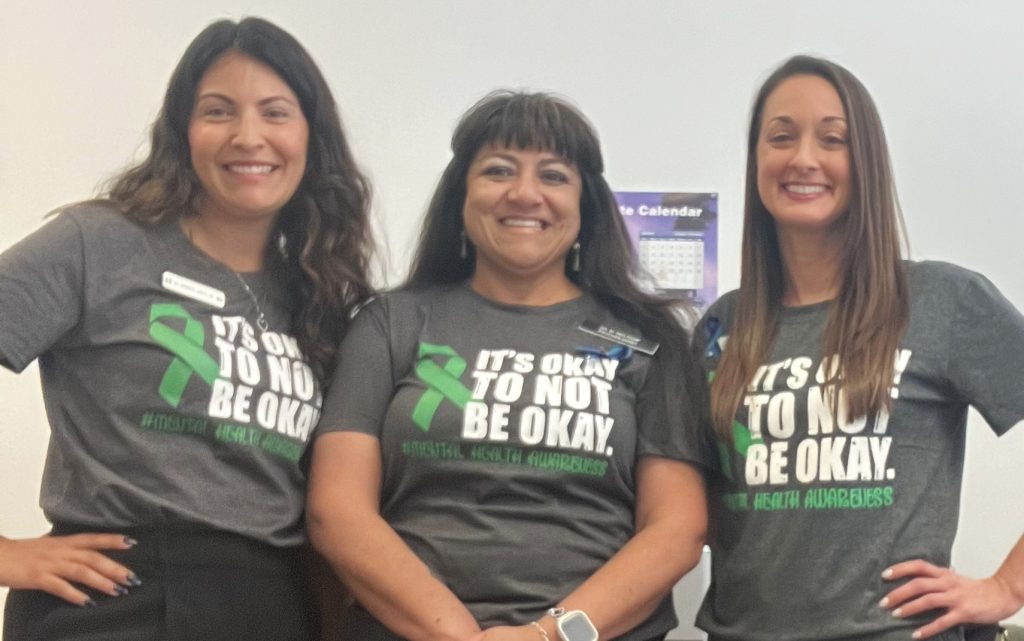 Three women wear shirts with the words "It's OK not to be OK."