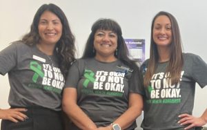 Three women wear shirts with the words "It's OK not to be OK."