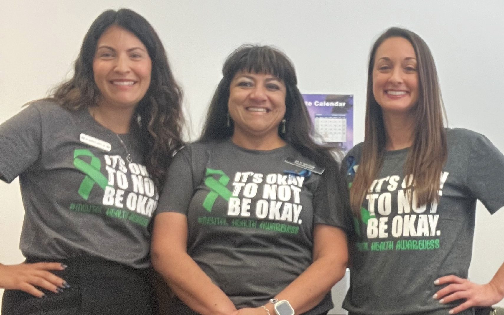 Three women wear shirts with the words "It's OK not to be OK."