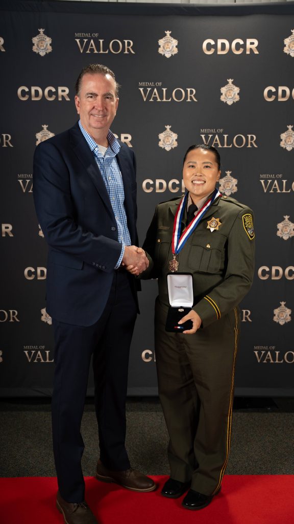 Officer Thao shakes hands with Secretary Macomber.