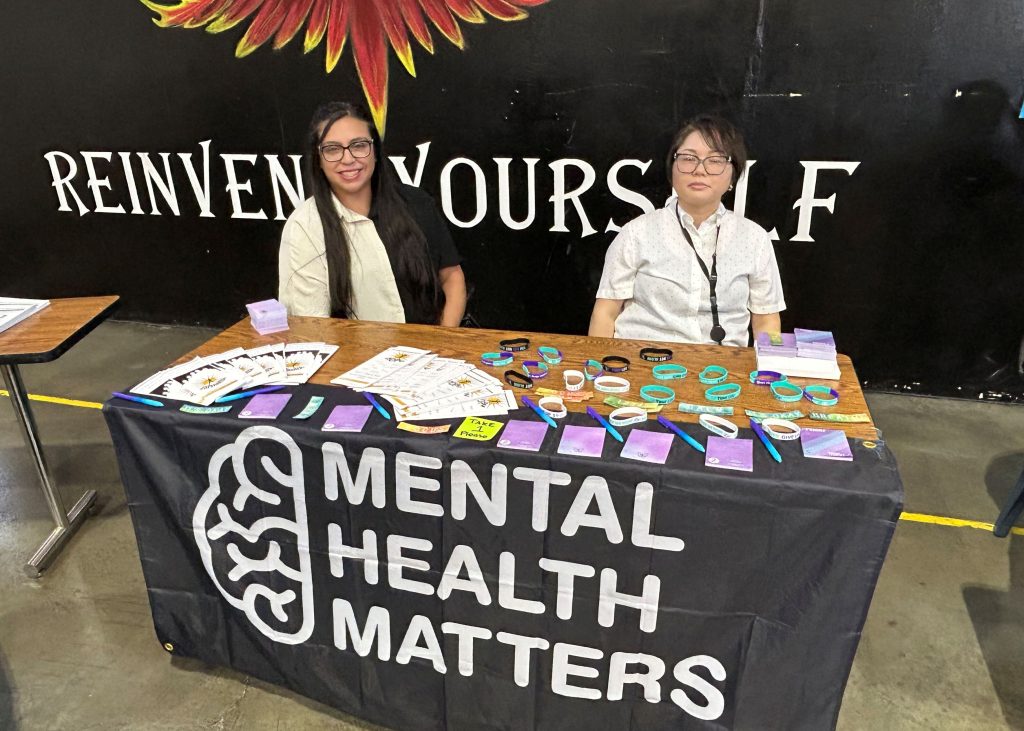Mental health resource table with staff at ASP health and wellness fair