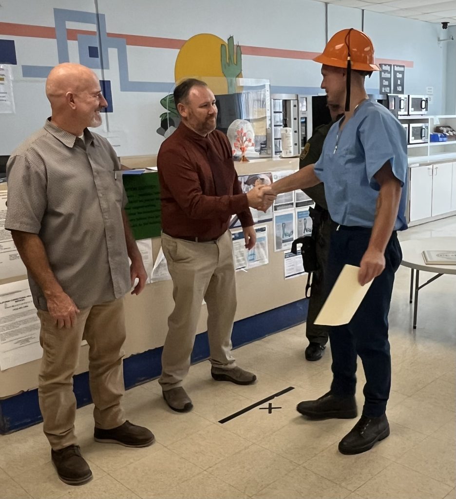 Incarcerated graduate receives certificate from staff