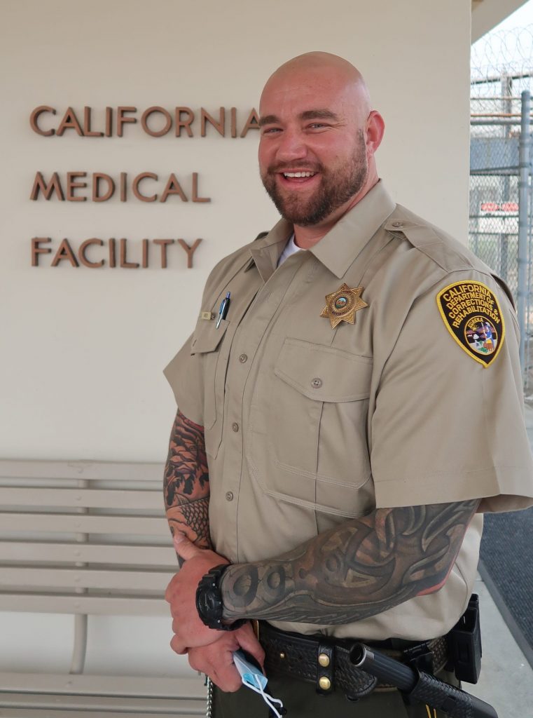 Man wearing uniform in from of sign for California Medical Facility.