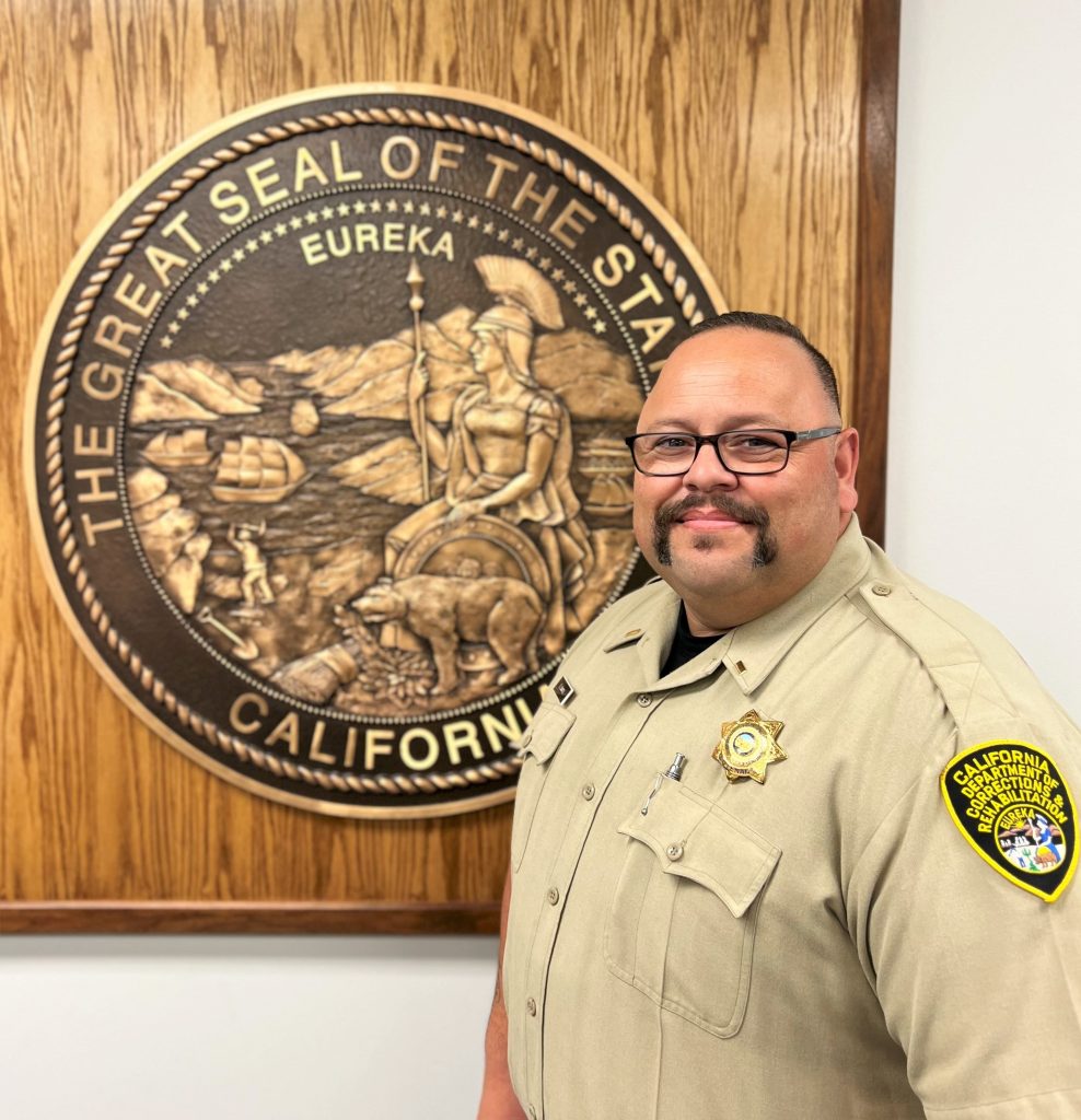 Lieutenant Cantu in front of a Great Seal of California.