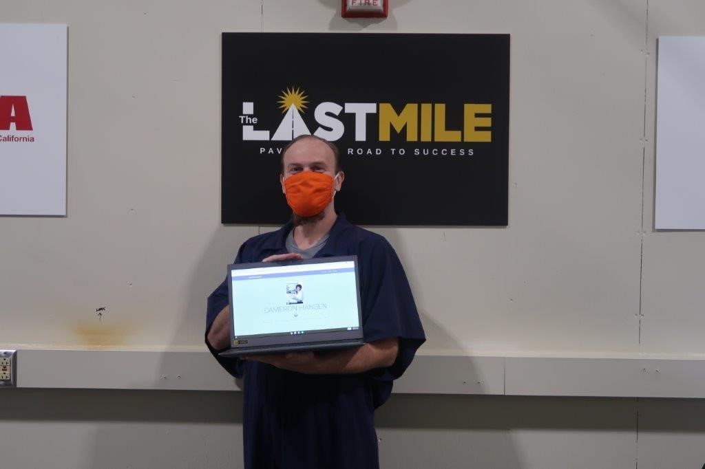 An inmate posing with a laptop from the Laptop Program.