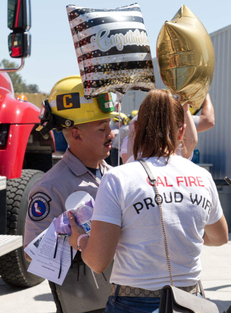 A VTC graduate with his wife wearing a shirt which reads 'CAL FIRE Proud Wife'