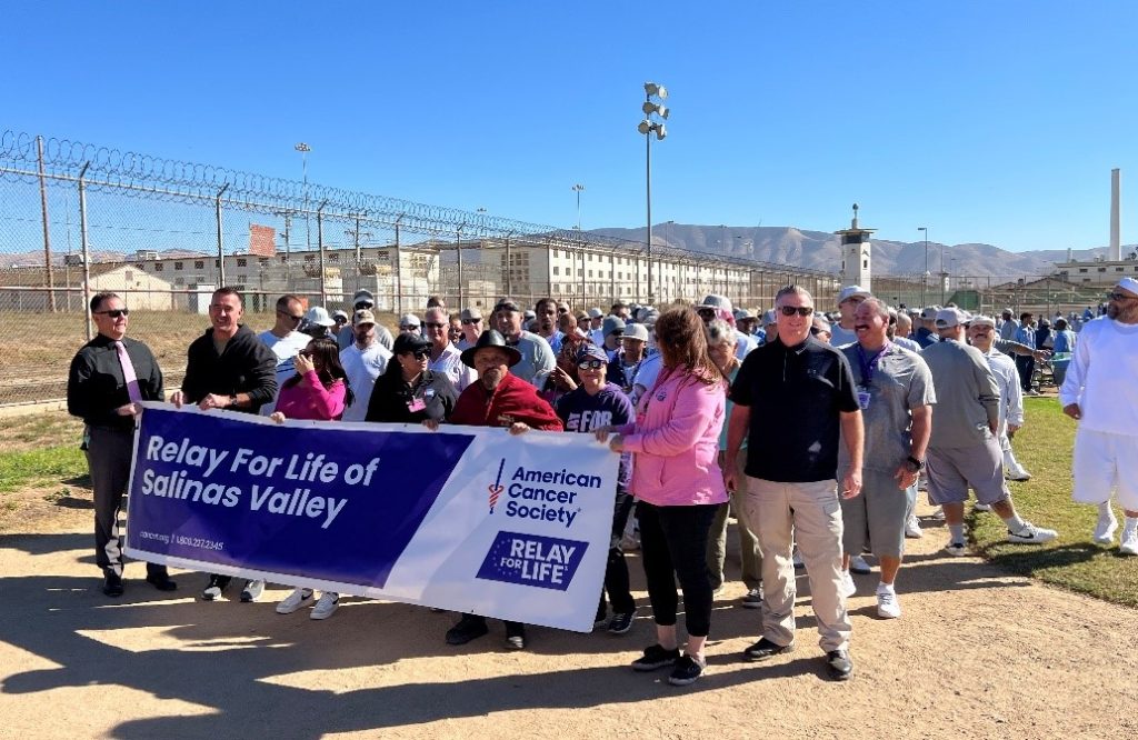 Staff, Volunteer, and Incarcerated stand behind Relay for Life banner