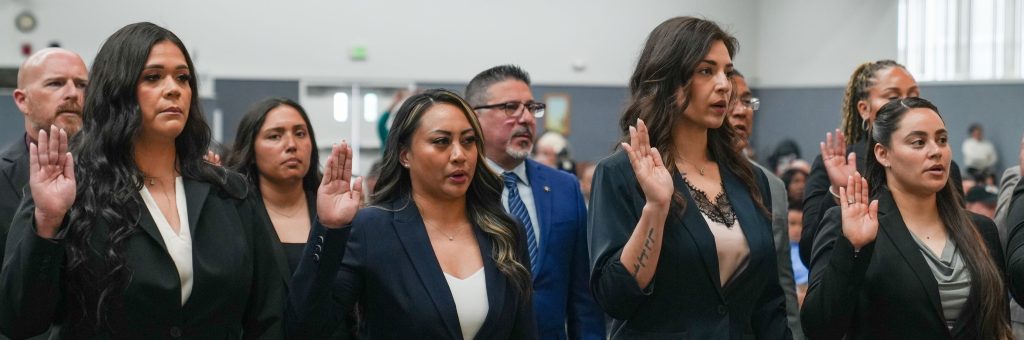 Four female graduates raising their right hand