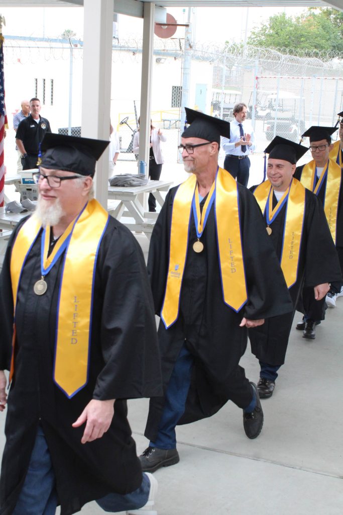CRC UCR graduates walking in cap and gown