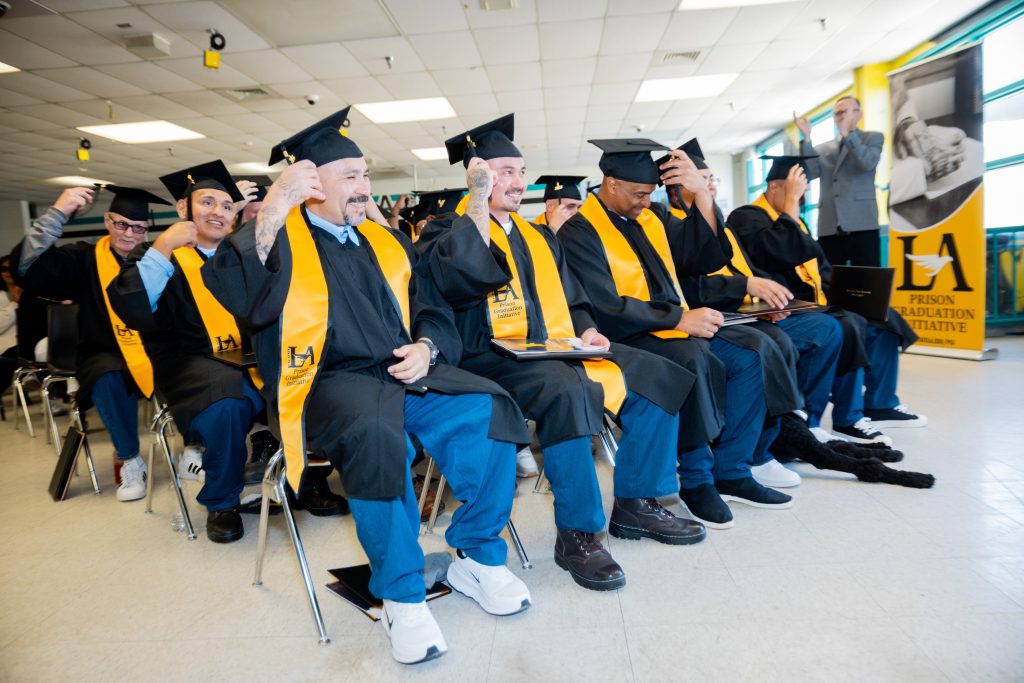 LAC PGI graduates seated during ceremony, moving tassles on graduation caps