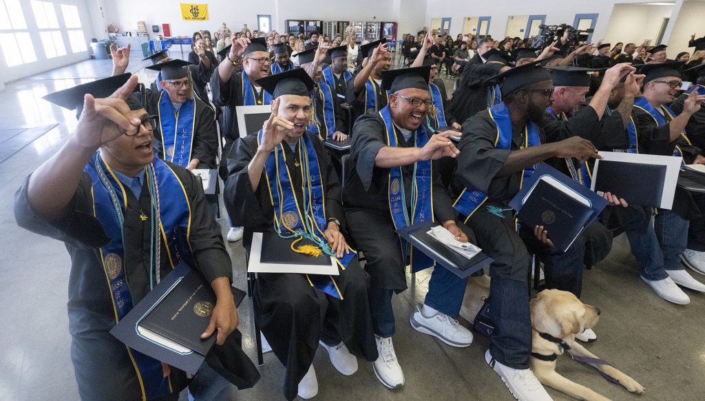 RJD UCI grads cheering with hands up