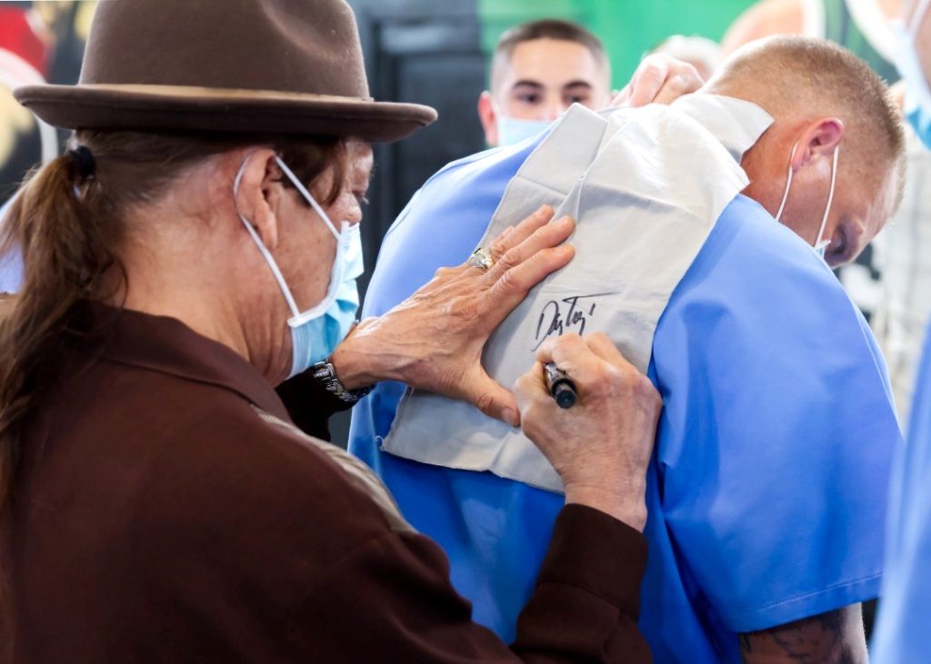Actor Danny Trejo signs an autograph on the back of an incarcerated person.