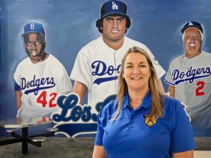 Recreational Coordinator Heidi Wippel , woman wearing blue shirt. Standing in front of mural of the LA Dodgers, showcasing three players.