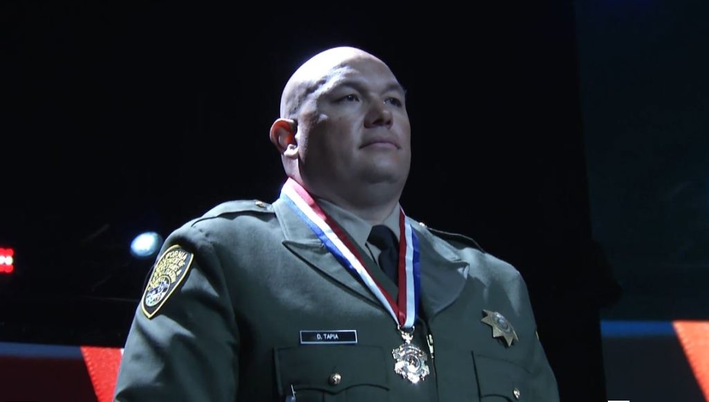 A correctional officer wears a red, white and blue Medal of Valor around his neck