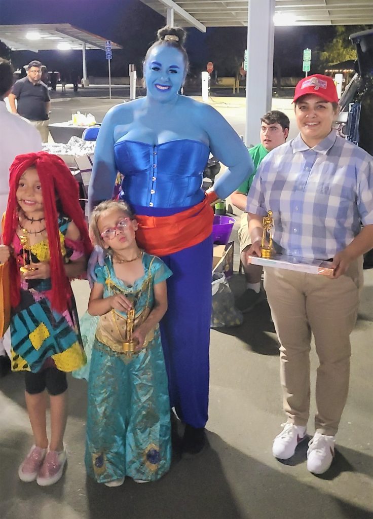 A woman dressed as a genie with children in costumes (Sally from Nightmare Before Christmas, Forrest Gump, Princess Jasmine)