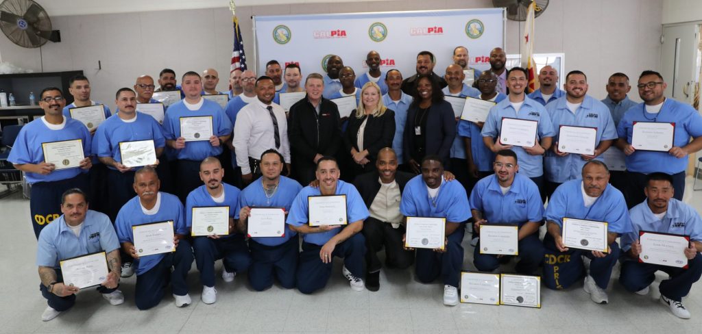 A group of incarcerated people and CDCR staff hold grduation certificates