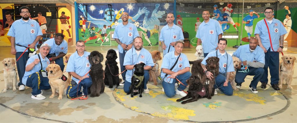 A group photo of incarcerated men and their dogs