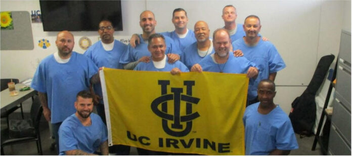 A group of incarcerated people hold a sign that says "UC Irvine"