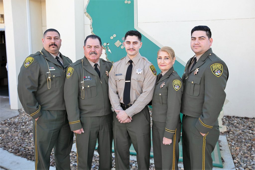 Four men and a woman in correctional uniforms