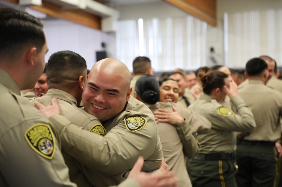People in correctional officer uniforms hug.