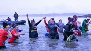 People in superhero costumes jump into a lake