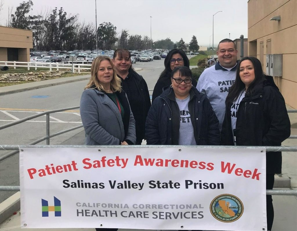 A group of people behind a Patient Safety Awareness Week sign