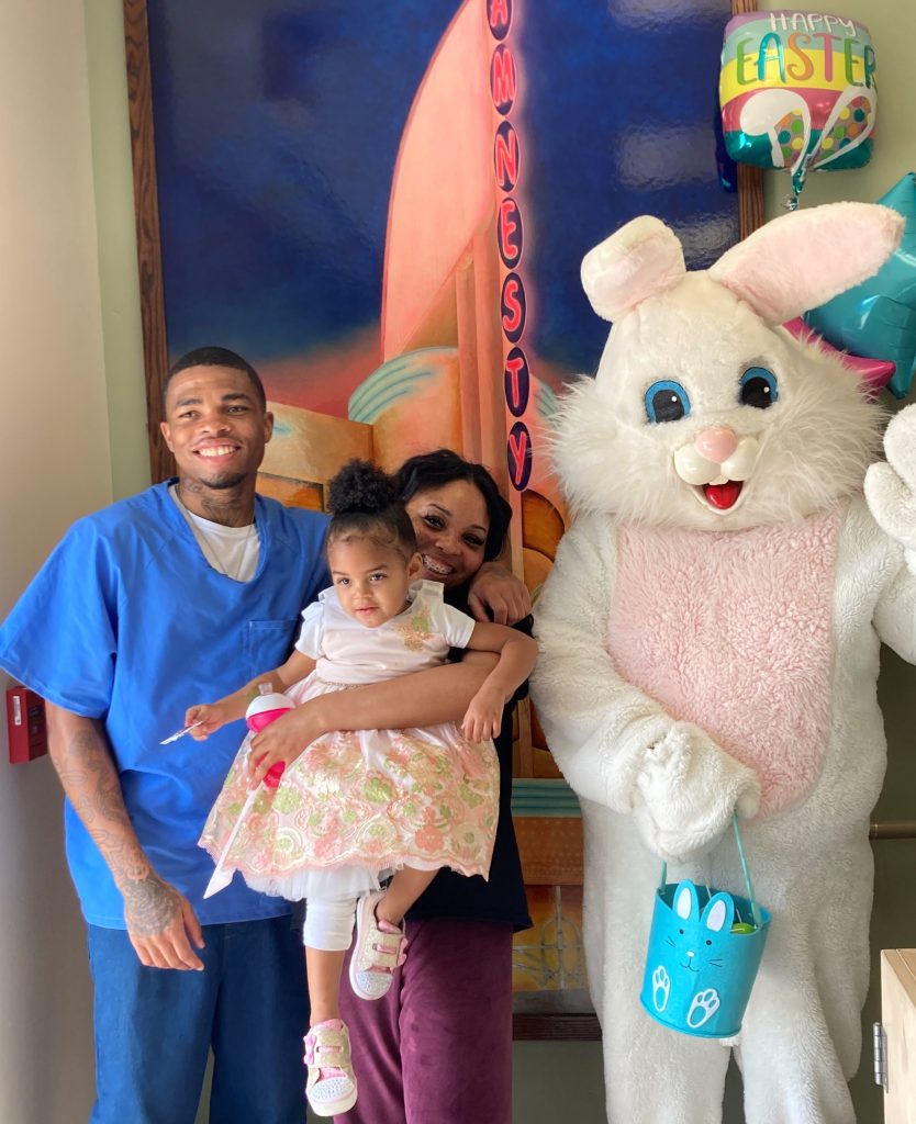A family of three poses with the Easter Bunny,