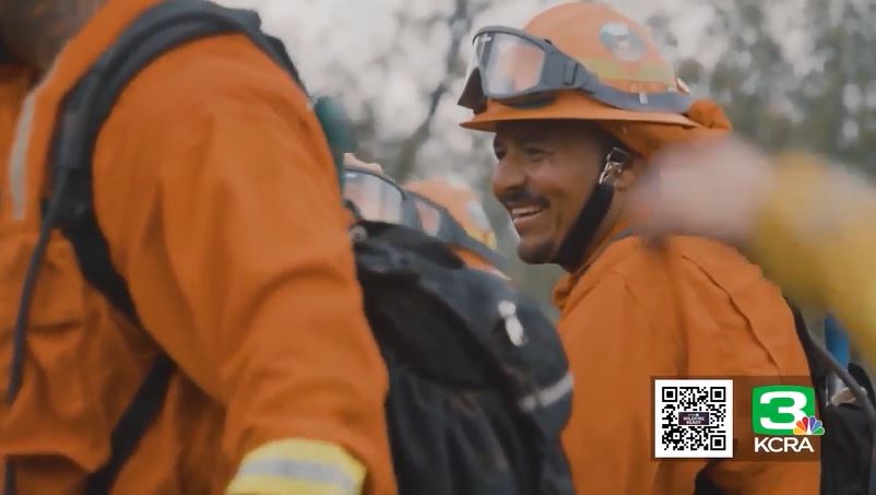 A smiling incarcerated firefighter in an orange uniform.