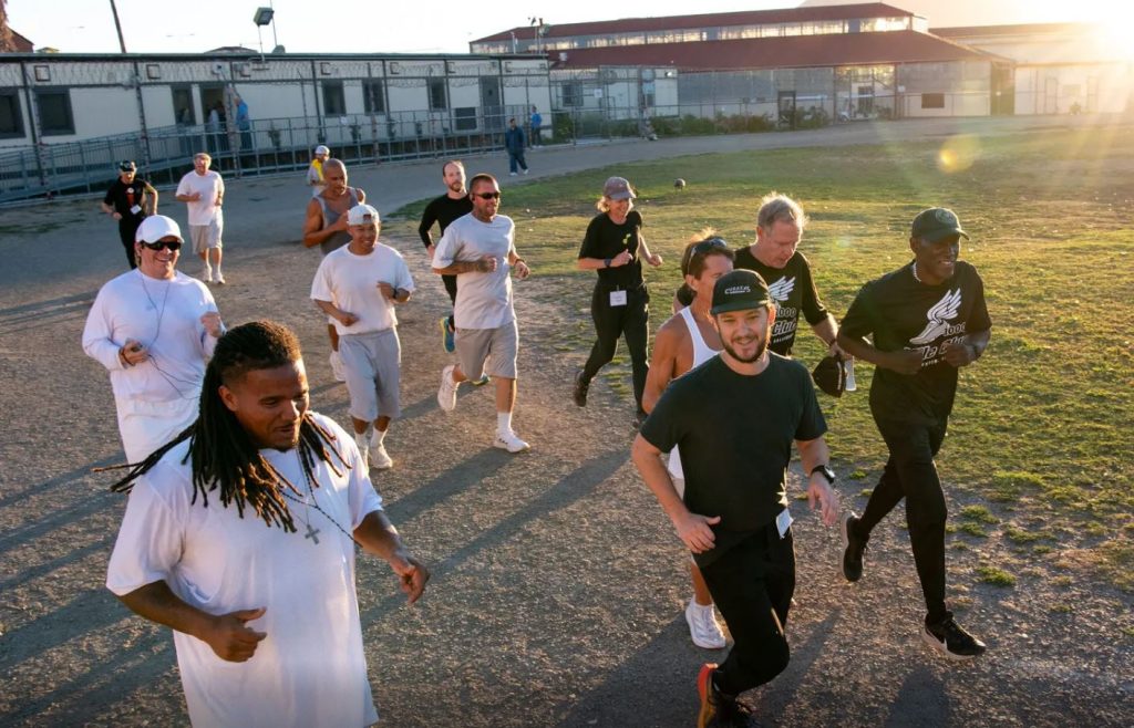 A group of runners on a dirt track in a prison yard.