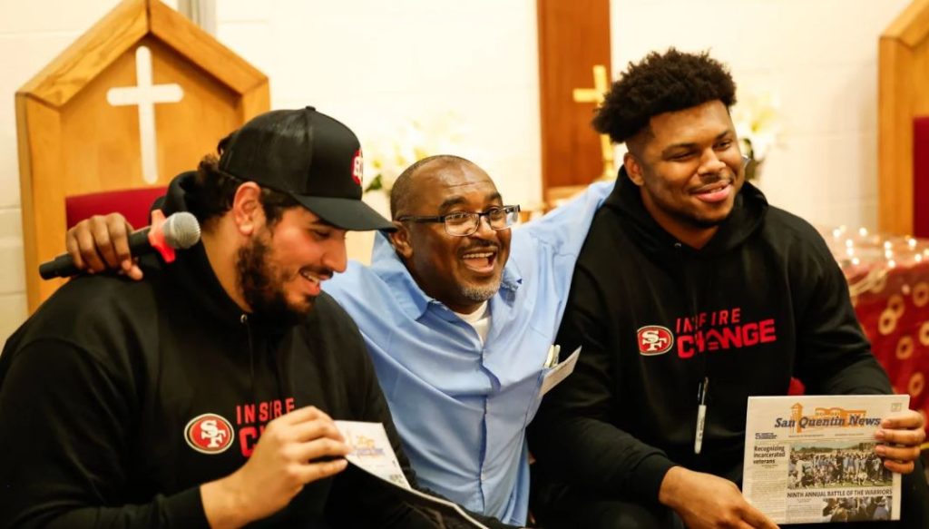 Two men in black 49ers hoodies with an incarcerated person.