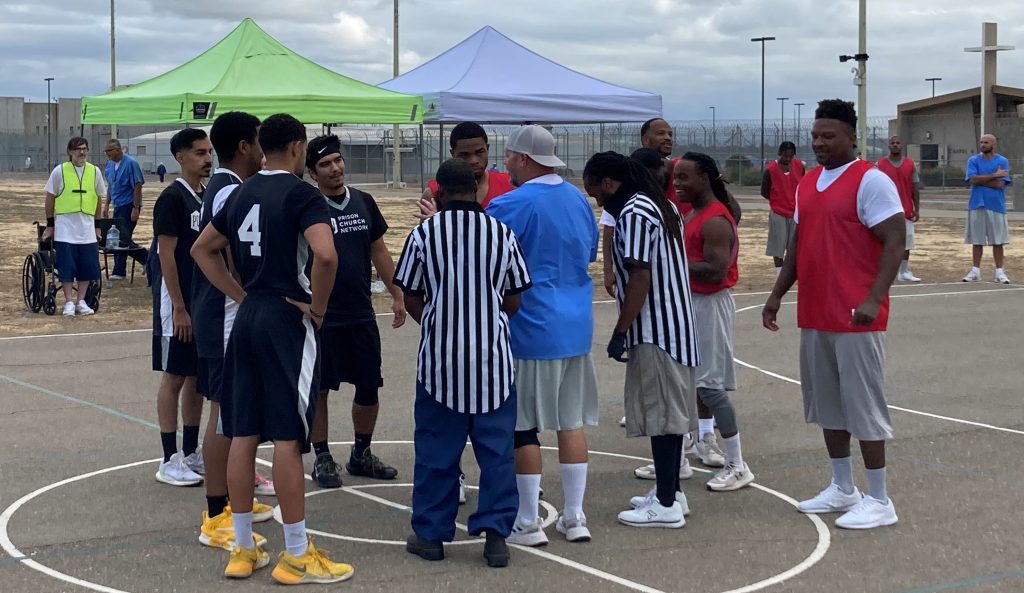 basketball players and two referees huddle up before a game