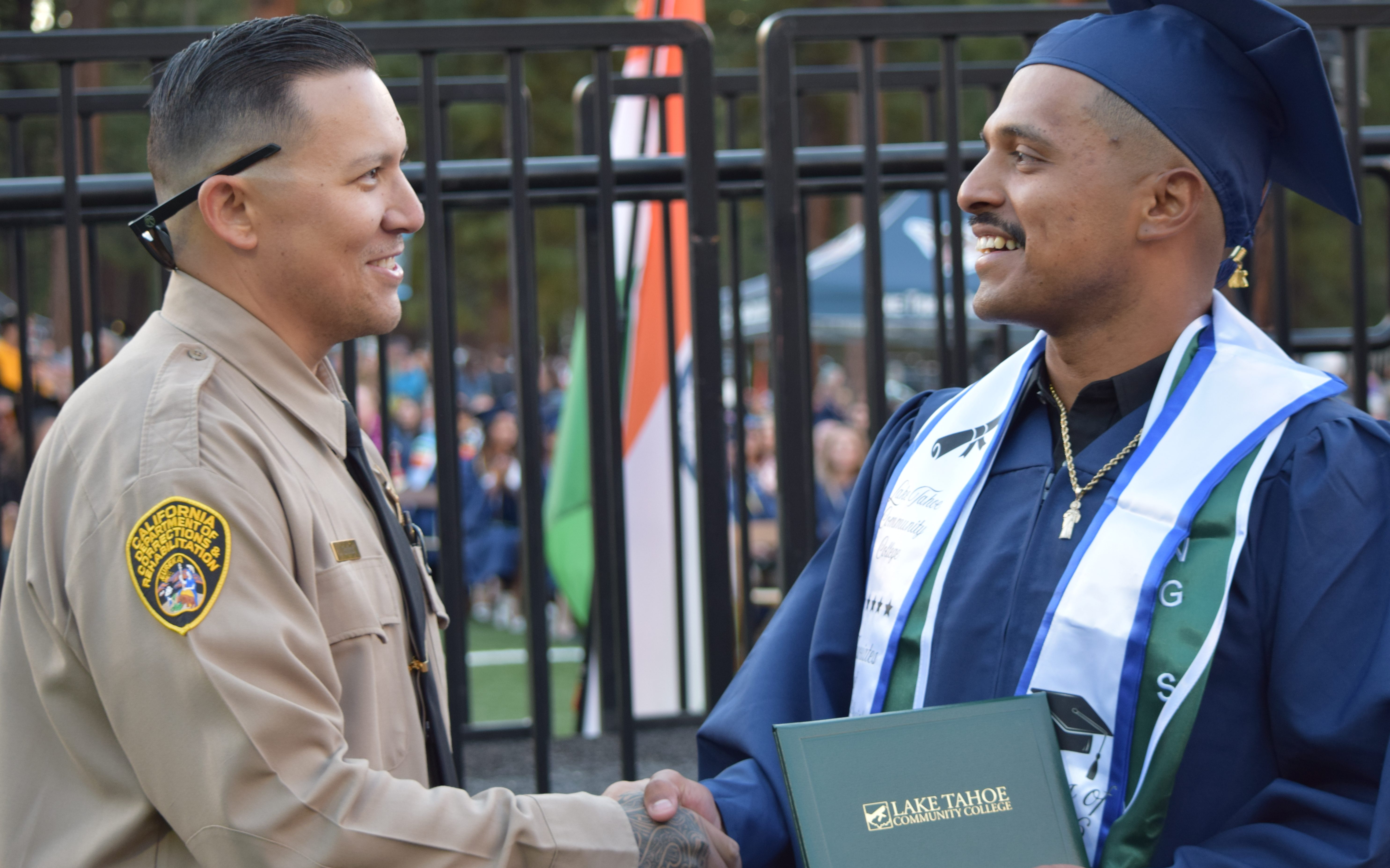 A correctional officer shakes hands with an incarcerated student who received his forestry degree from Lake Tahoe Community College's Rising Scholars Program.